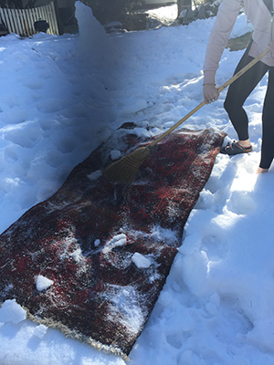 cleaning a rug by sweeping snow over it